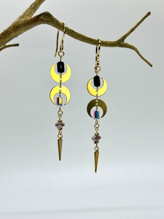 Earrings with gold crescent moon designs and black stones hanging from a branch.