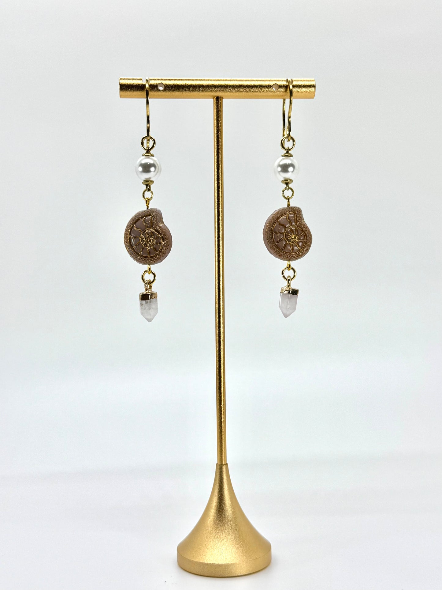 Pair of earrings on a gold stand against a white background