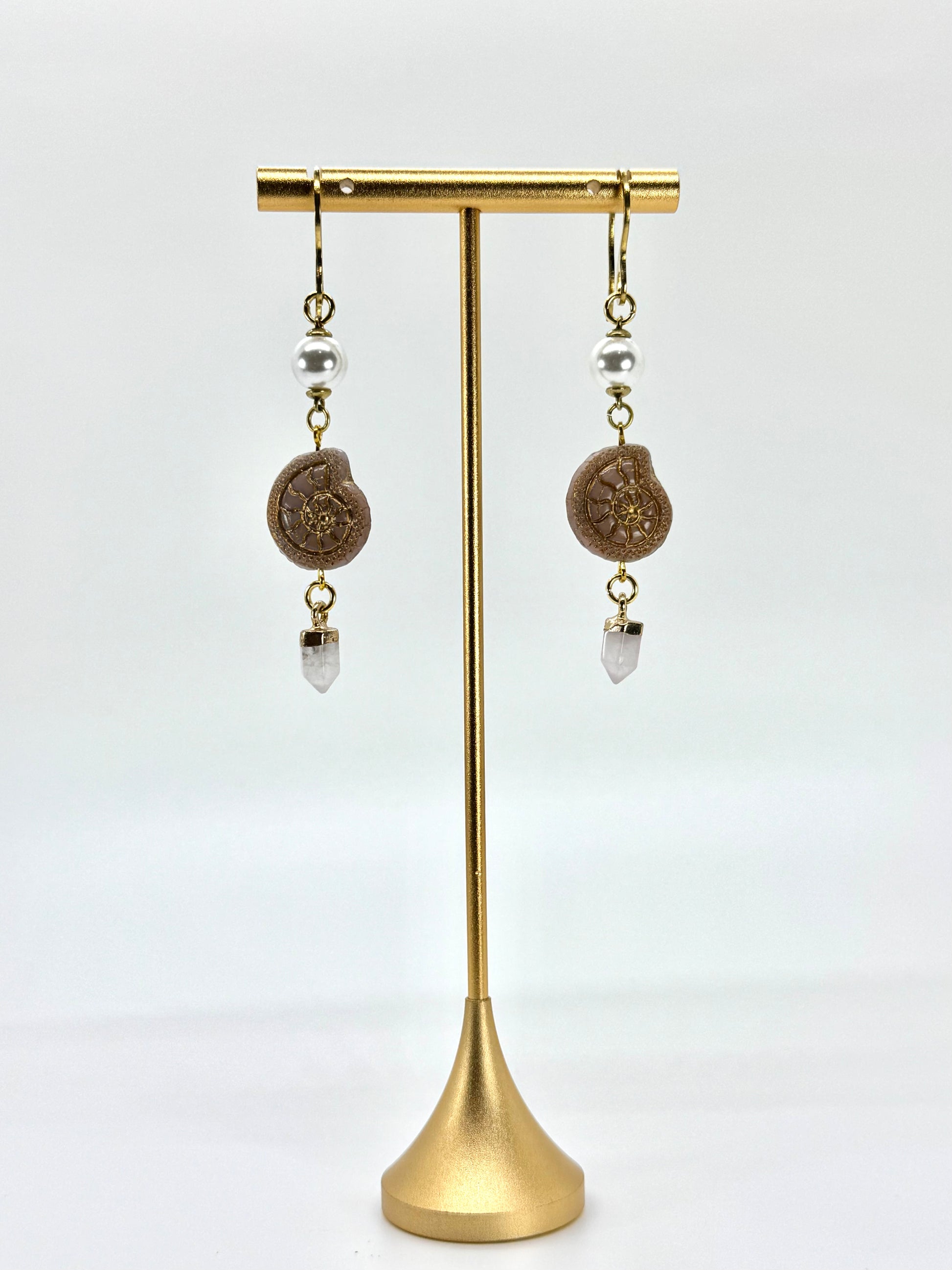 Pair of earrings on a gold stand against a white background