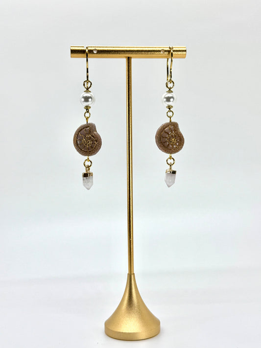 Pair of earrings on a gold stand against a white background