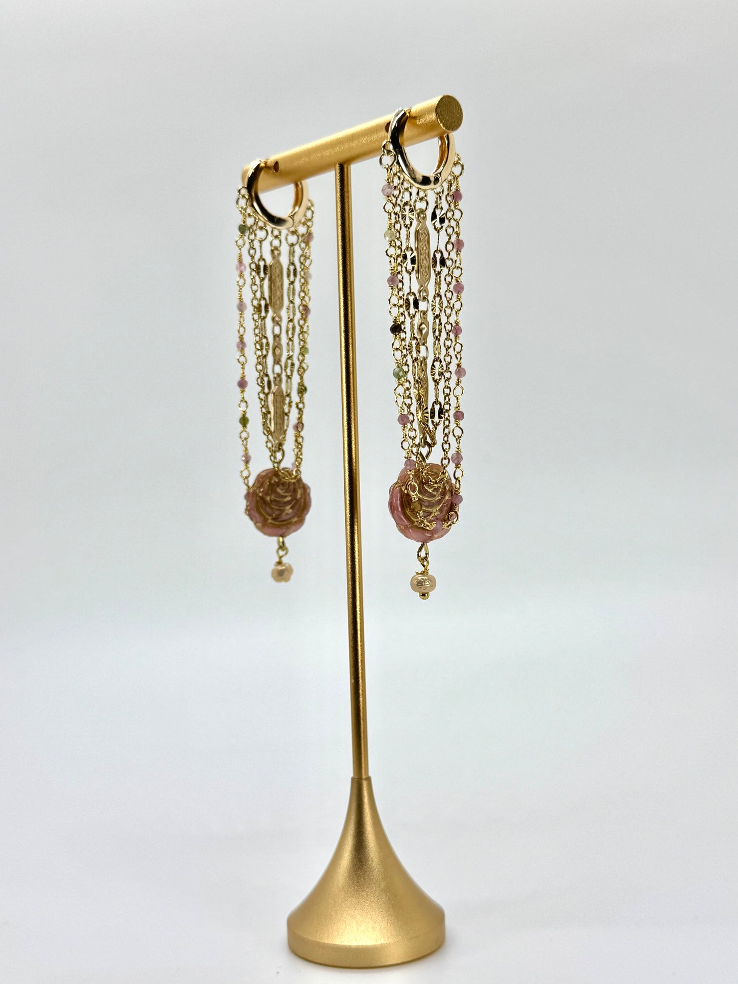Gold earring stand with hanging earrings on a white background