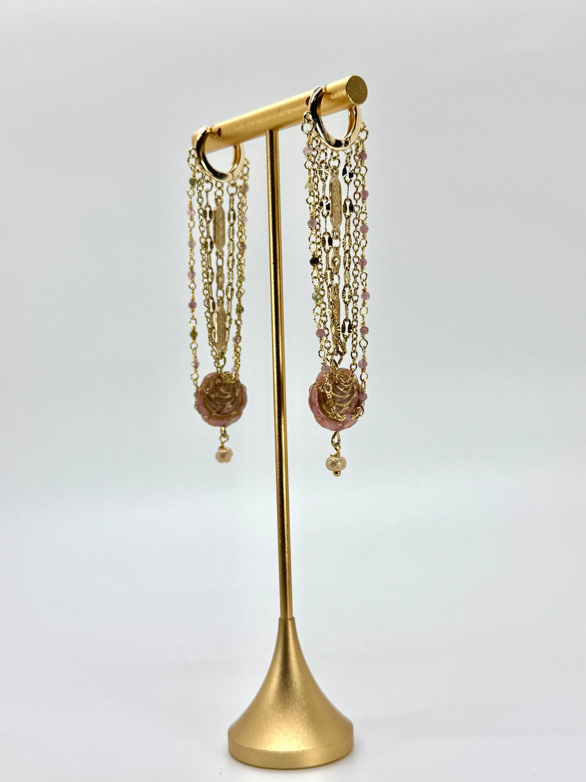 Gold earring stand with hanging earrings on a white background