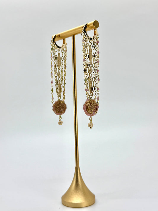 Gold earring stand with hanging earrings on a white background