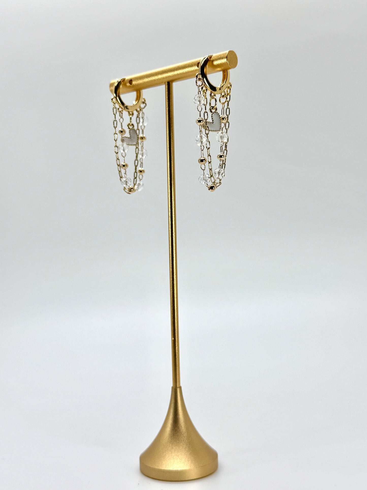 Gold earring stand with hanging earrings on a white background