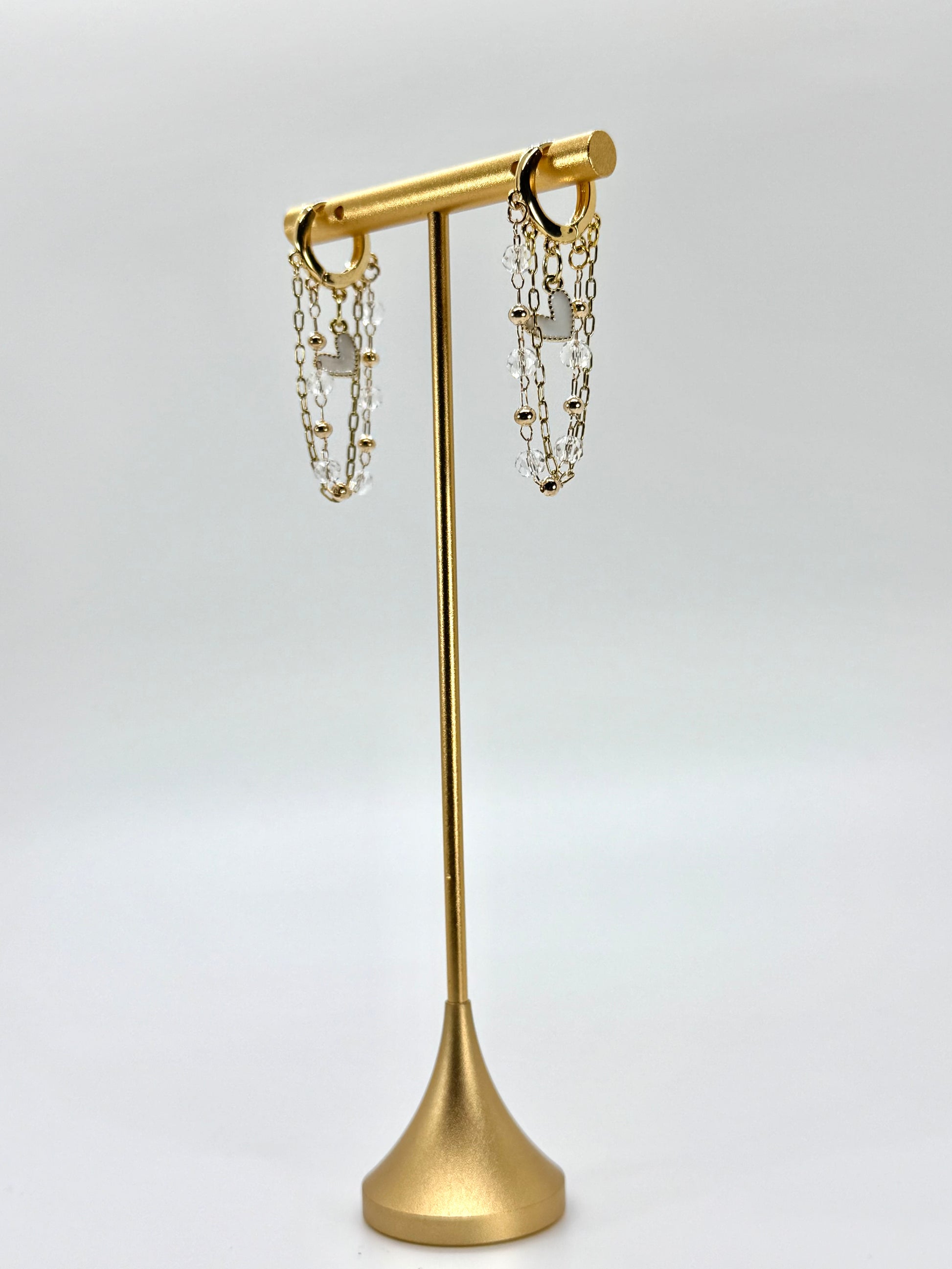 Gold earring stand with hanging earrings on a white background