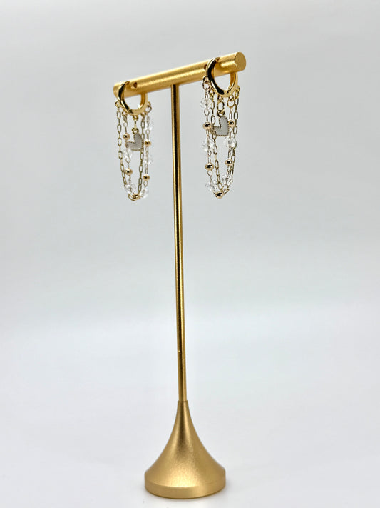 Gold earring stand with hanging earrings on a white background