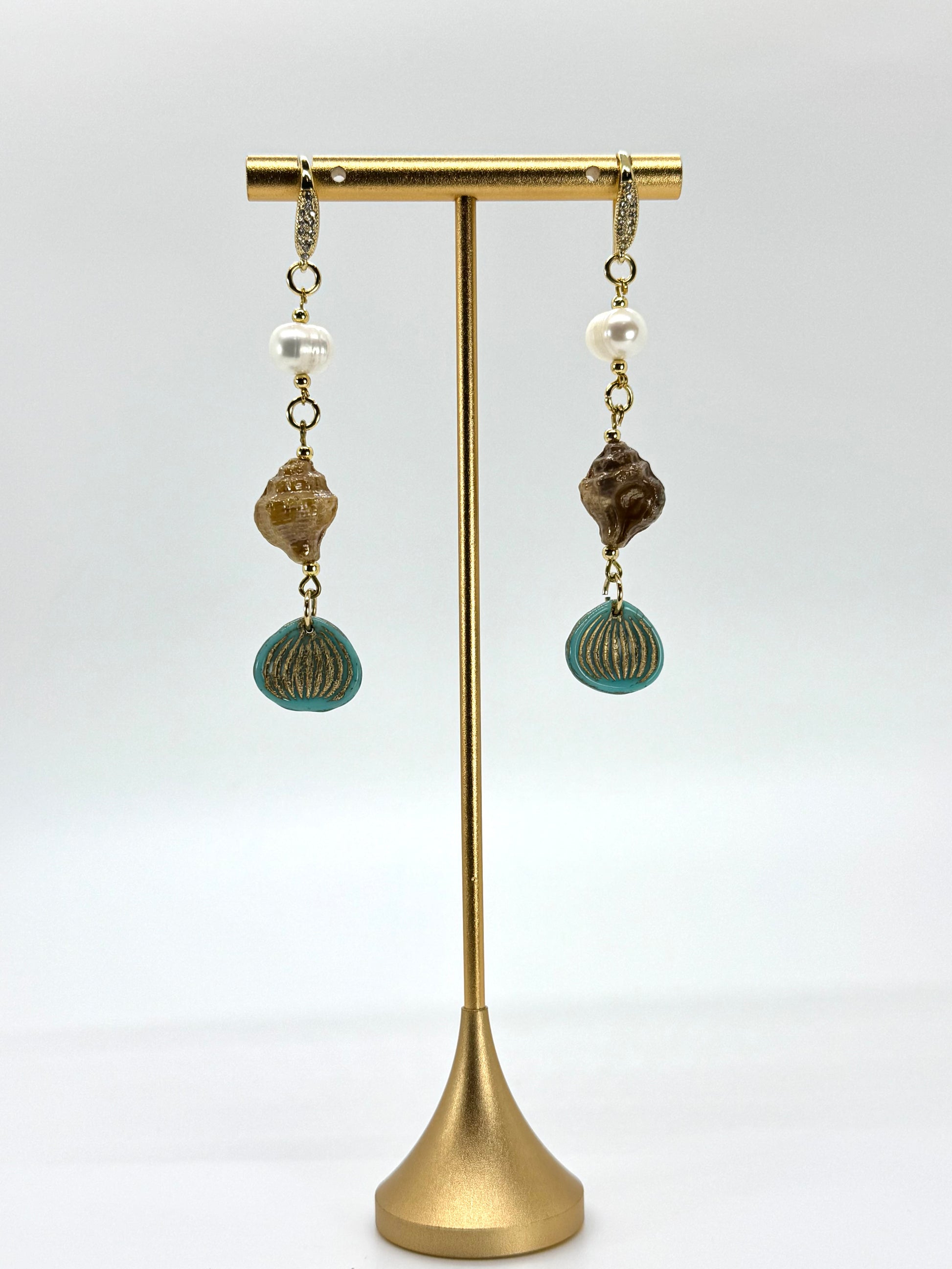 Pair of earrings with beads on a gold stand against a white background