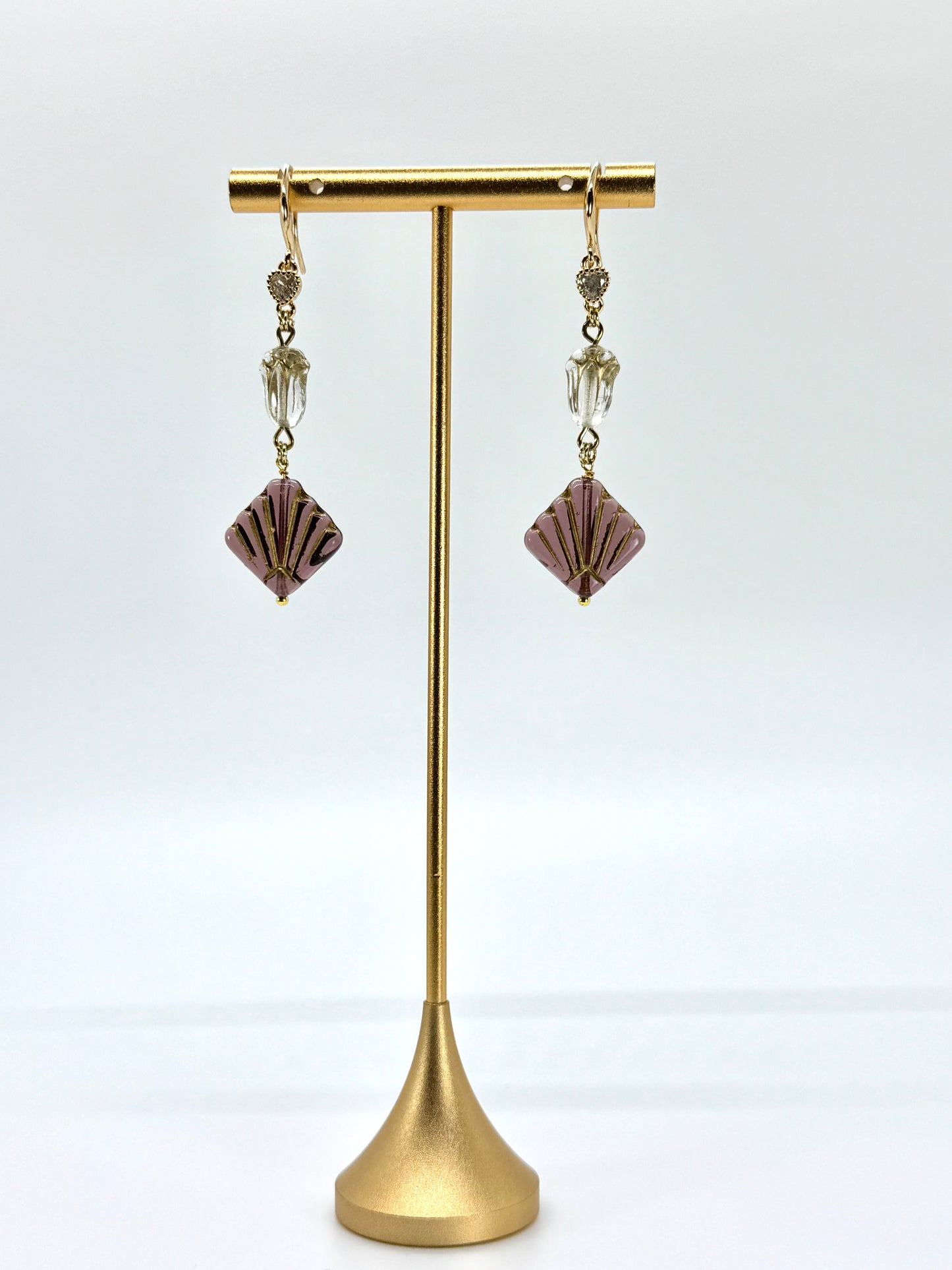 Pair of earrings on a gold stand against a white background