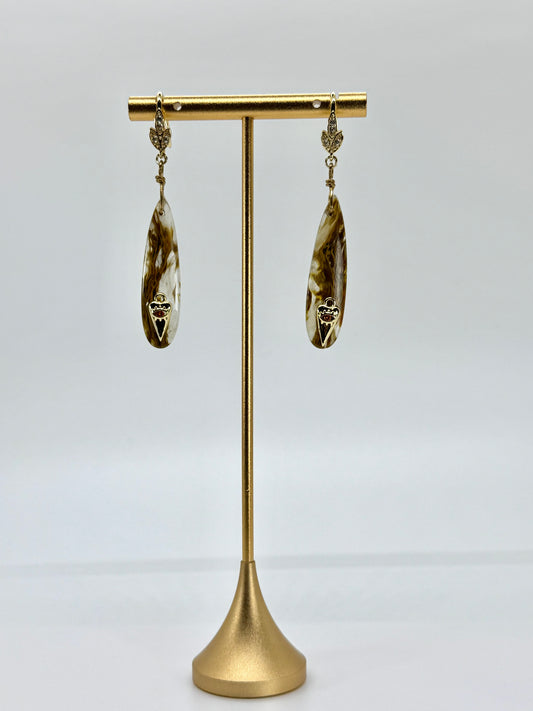 Pair of gold earrings on a gold stand against a white background
