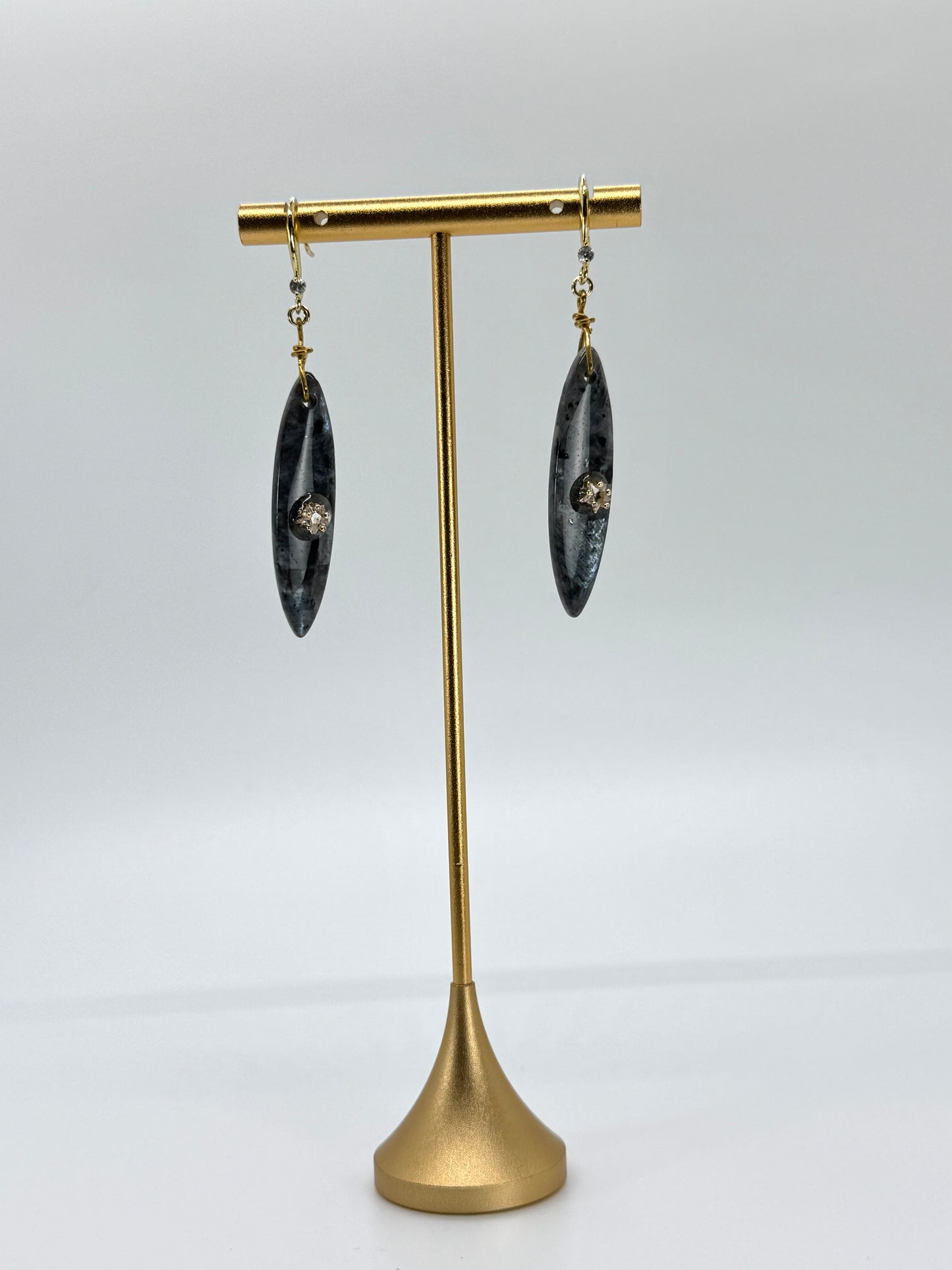 Pair of earrings on a gold stand against a white background