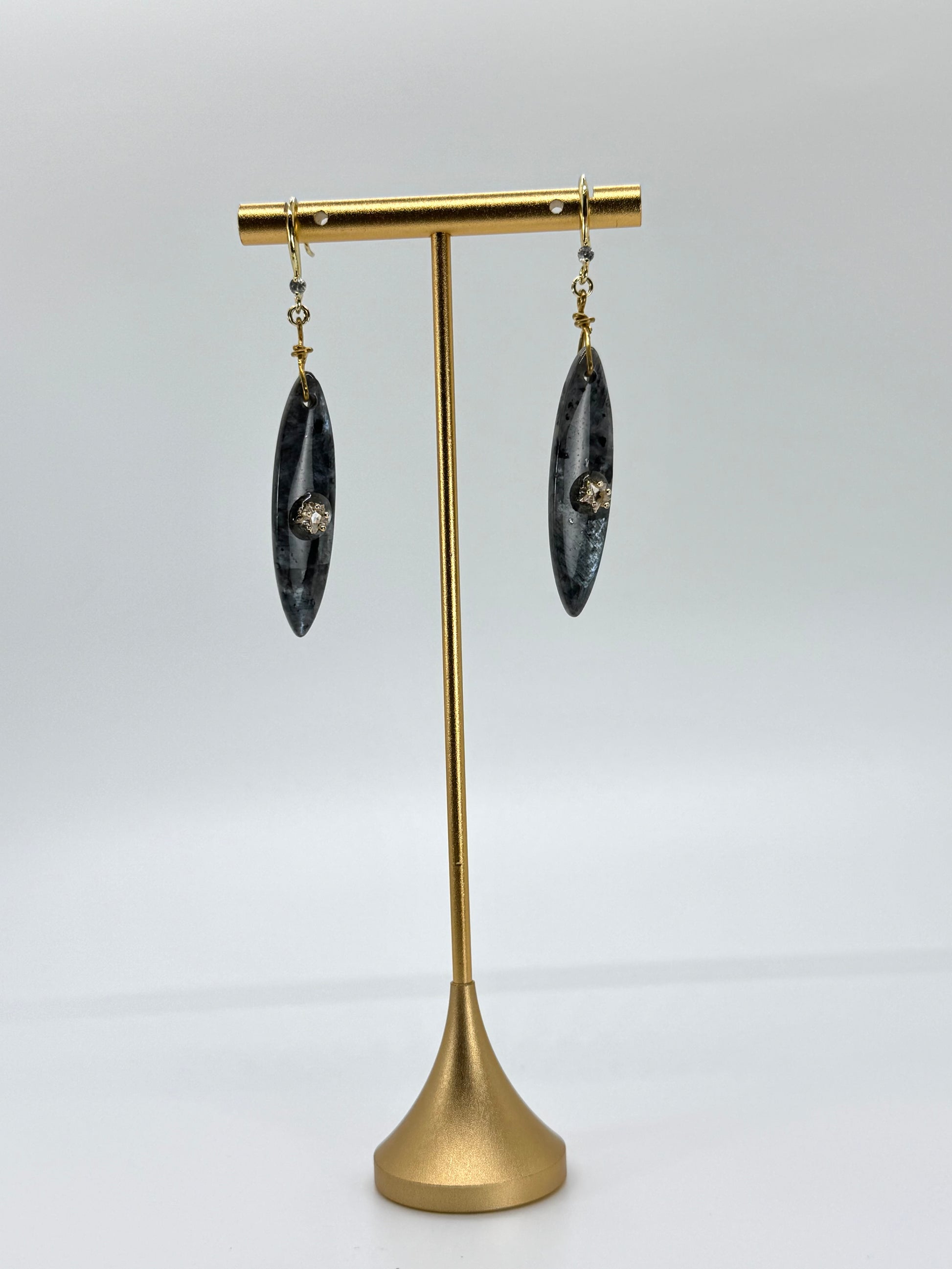 Pair of earrings on a gold stand against a white background