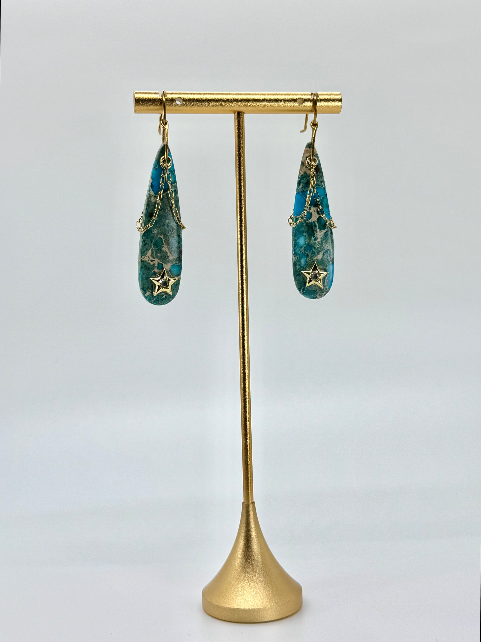 Gold earring stand with blue earrings on a white background