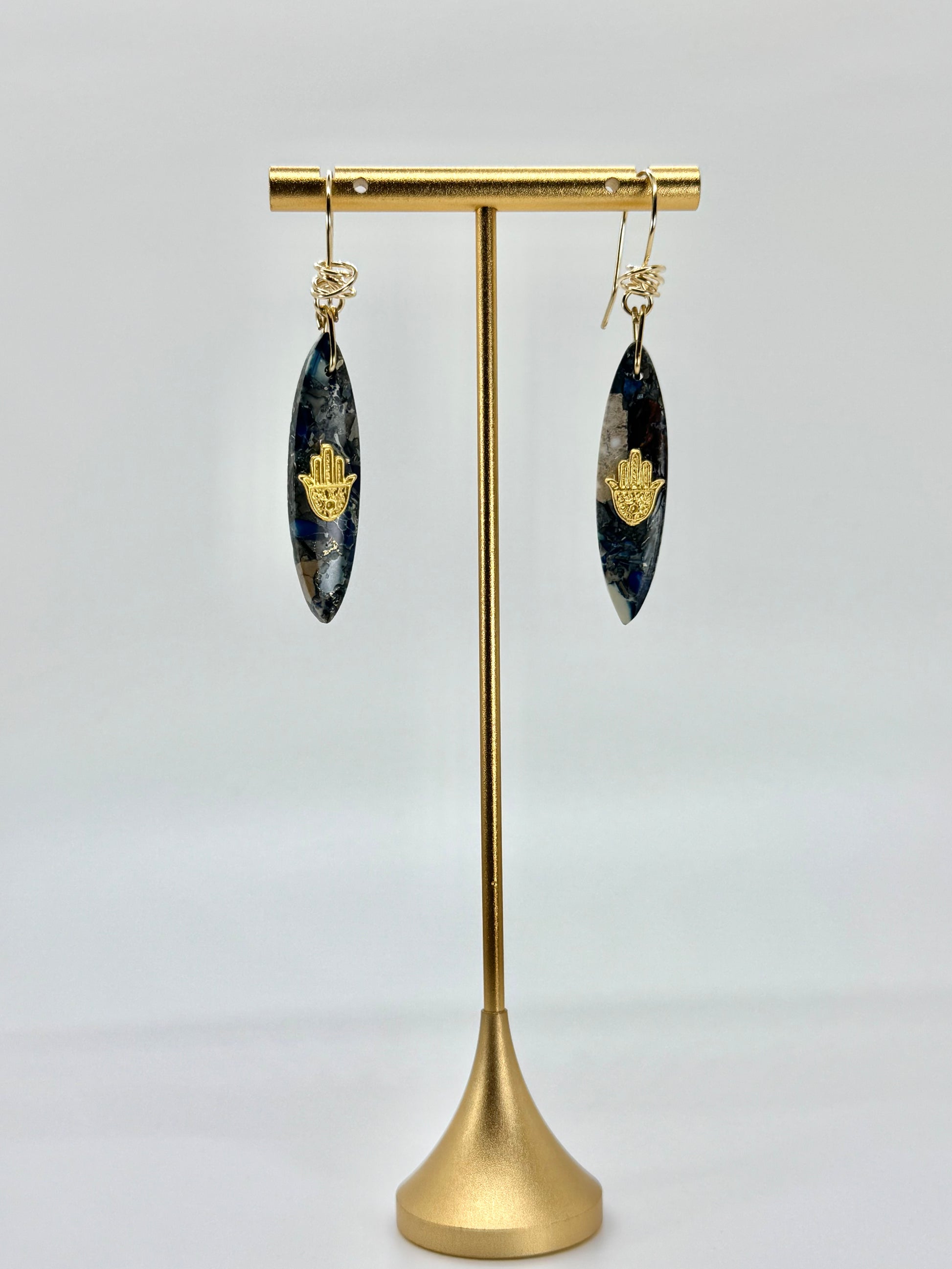 Pair of earrings on a gold stand against a white background