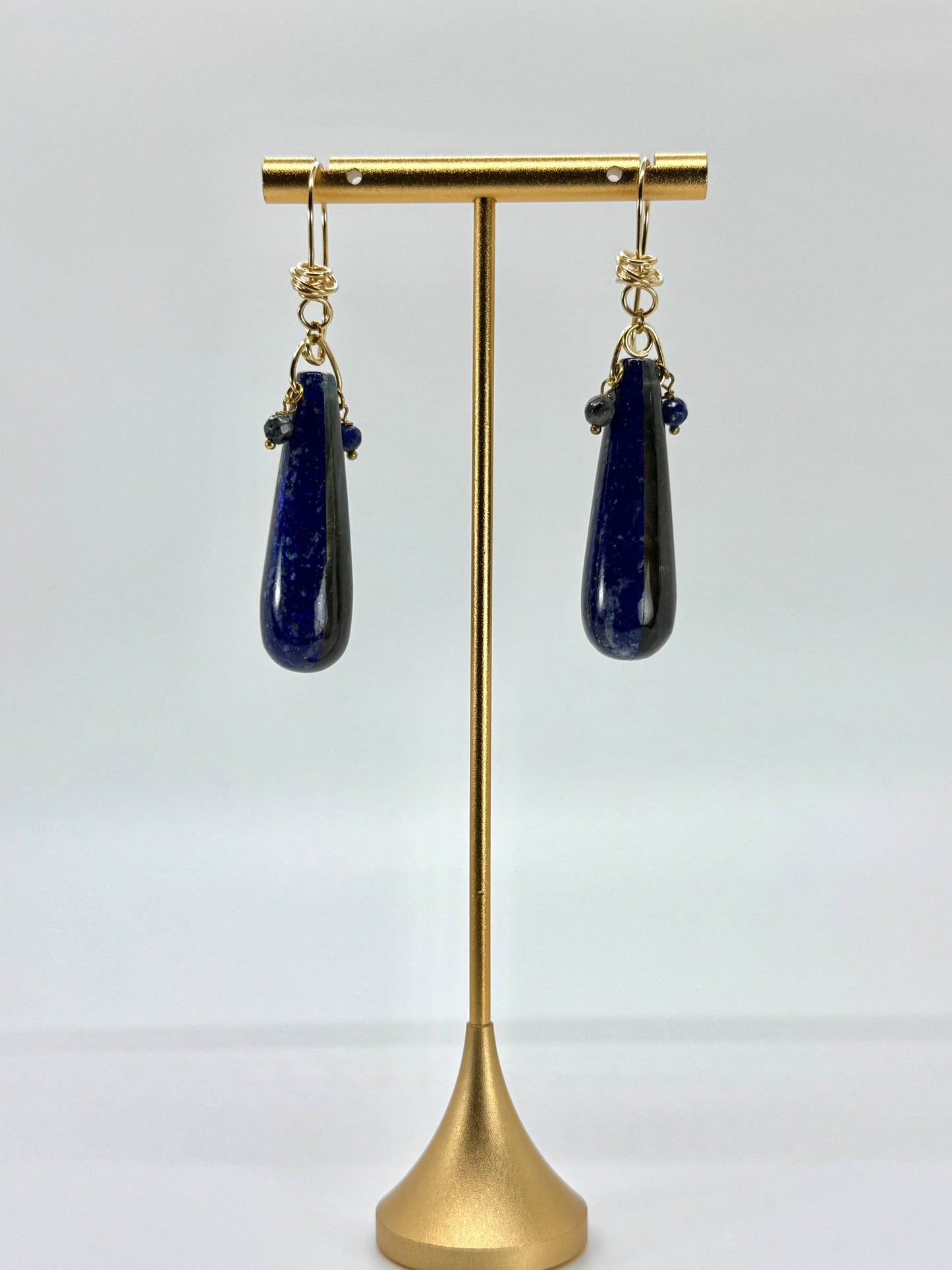 Lapis lazuli teardrop earrings on a gold stand against a white background