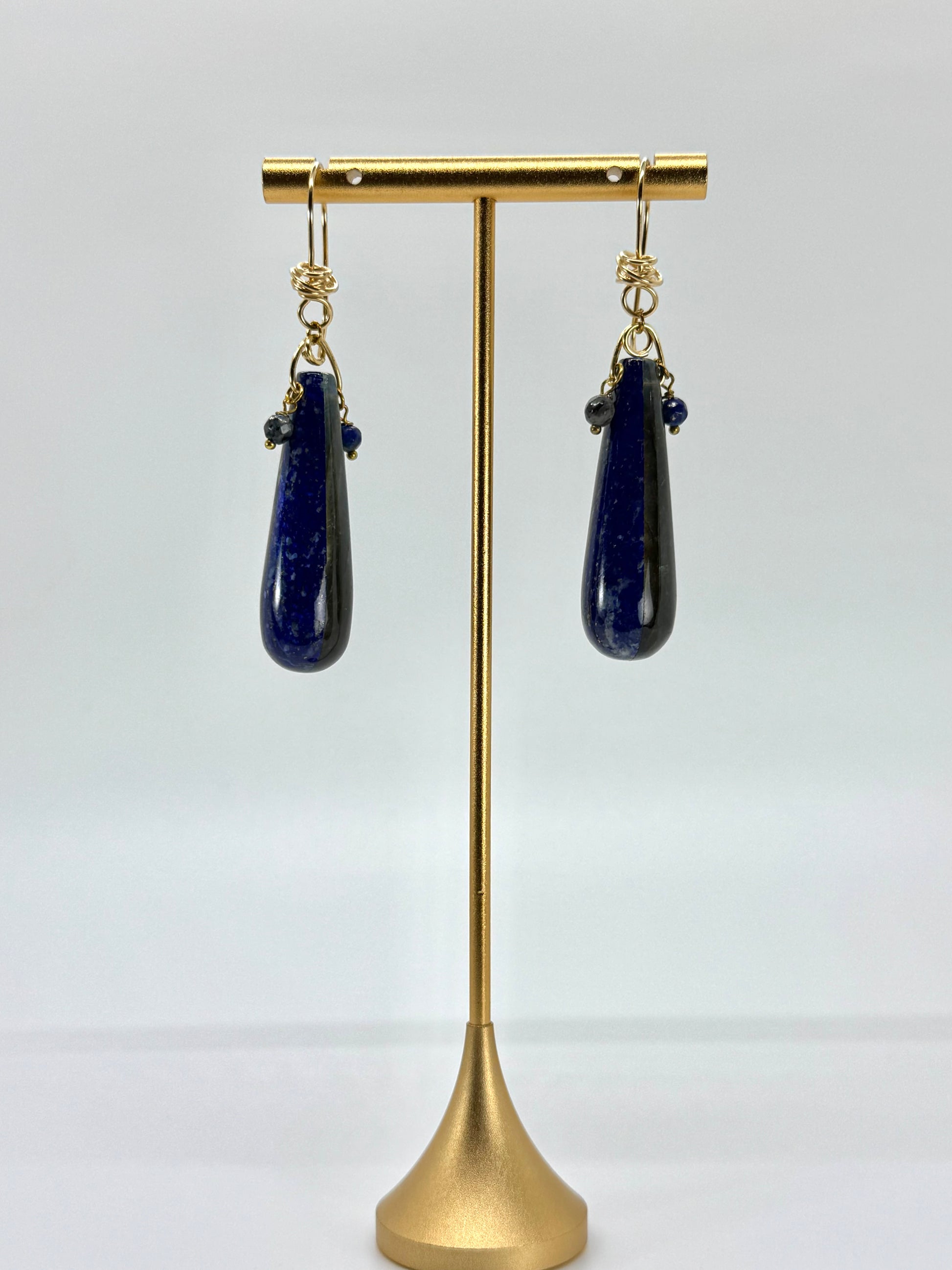 Lapis lazuli teardrop earrings on a gold stand against a white background