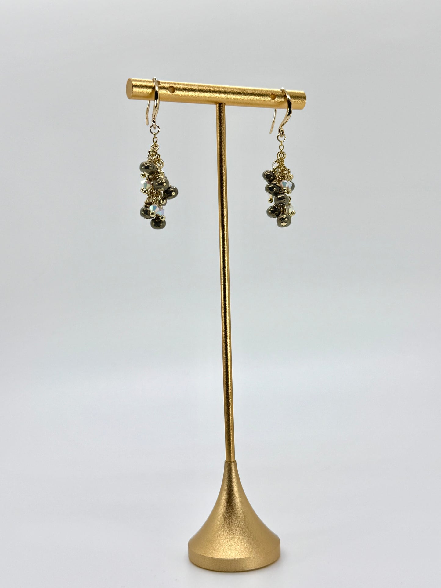 Gold earrings on a gold stand against a white background