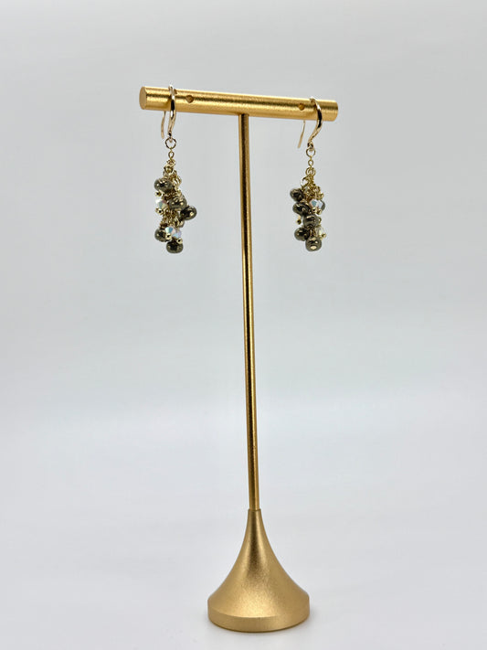 Gold earrings on a gold stand against a white background
