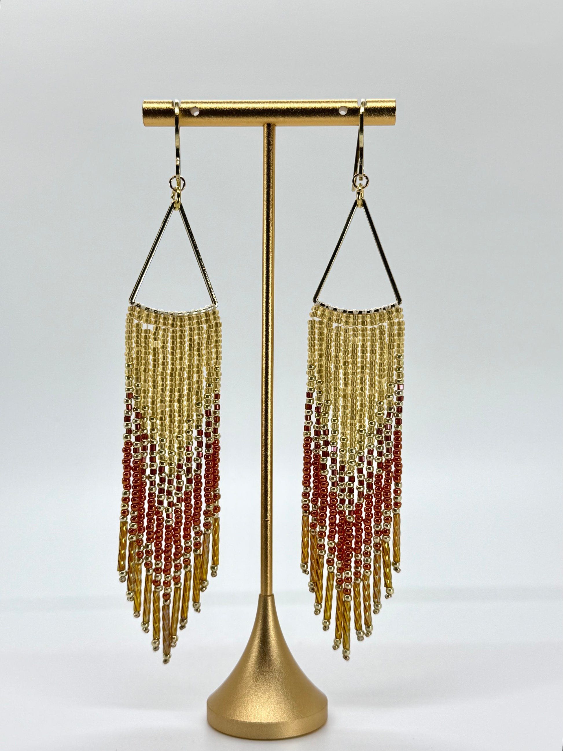 Beaded earrings on a gold stand against a white background