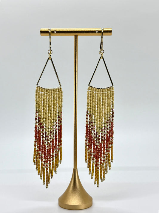 Beaded earrings on a gold stand against a white background