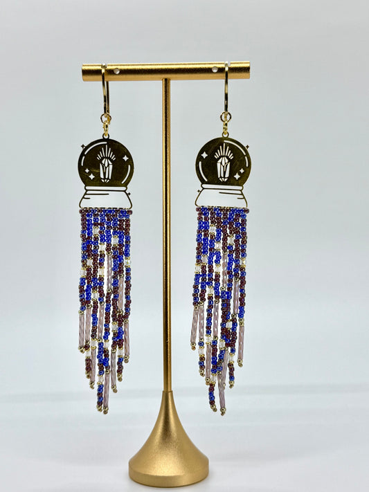 Beaded earrings on a gold stand against a gray background
