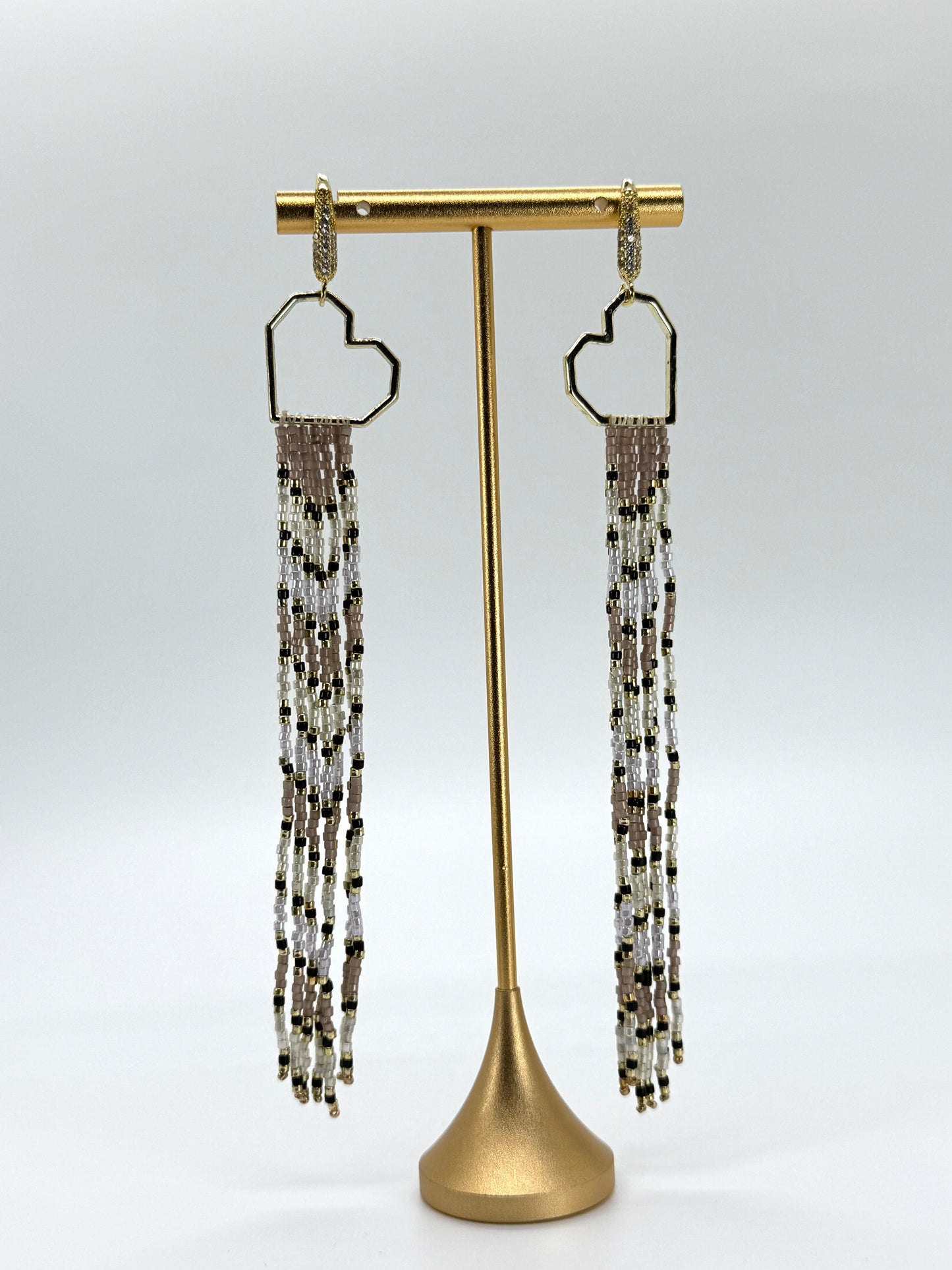 Beaded earrings on a gold stand against a white background