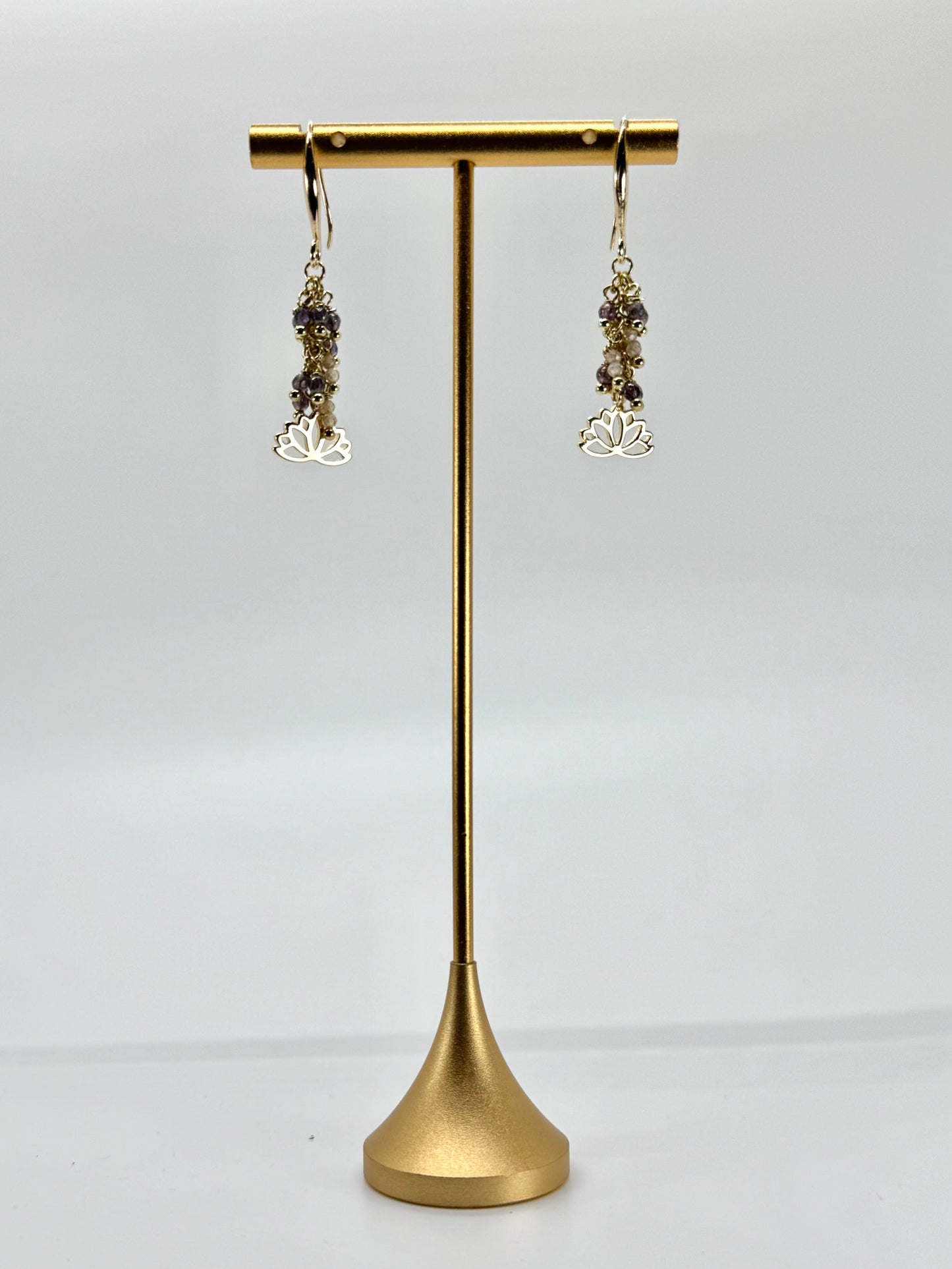 Gold earrings on a gold earring stand against a white background