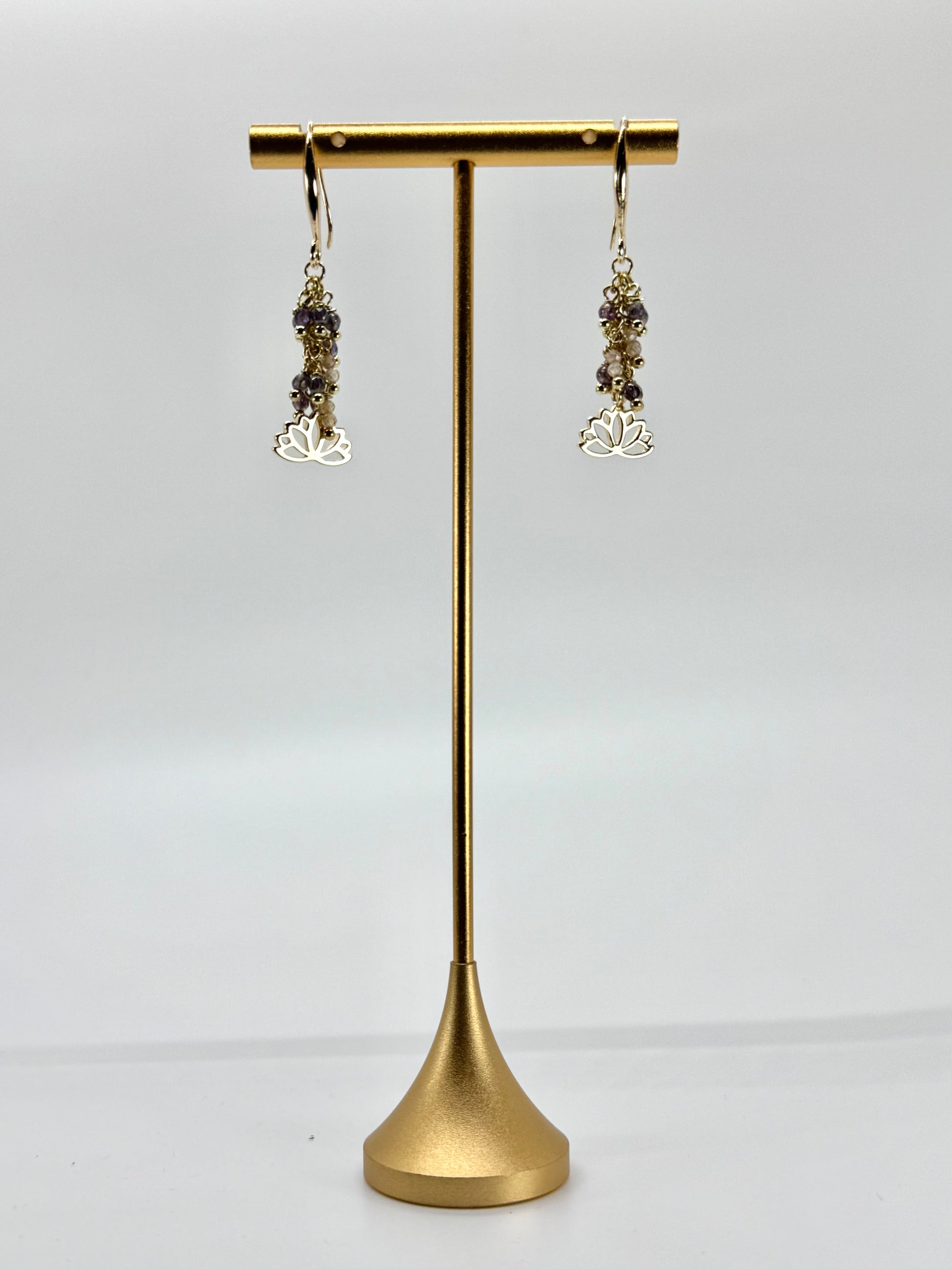 Gold earrings on a gold earring stand against a white background