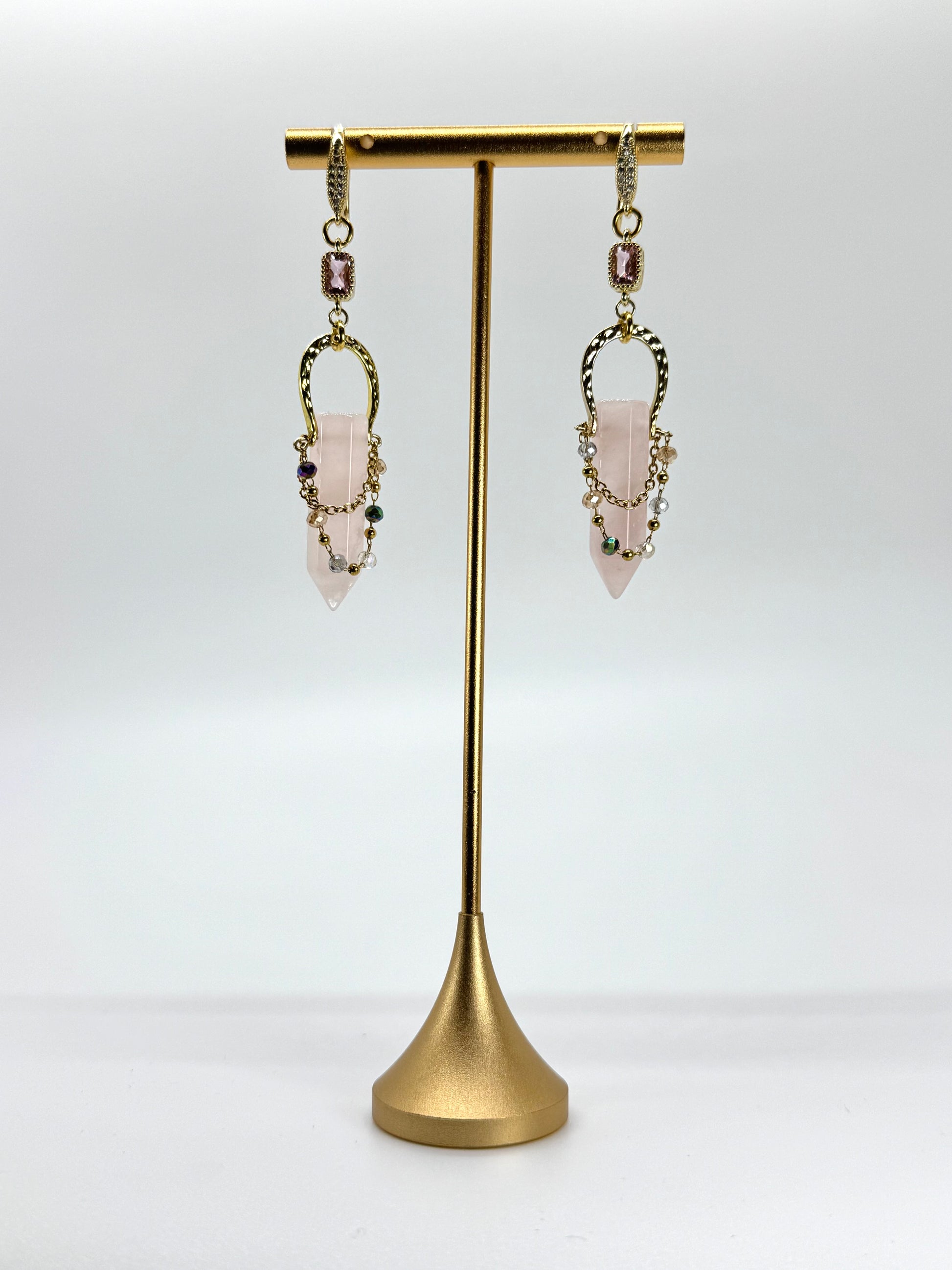 Pair of earrings on a gold stand against a white background