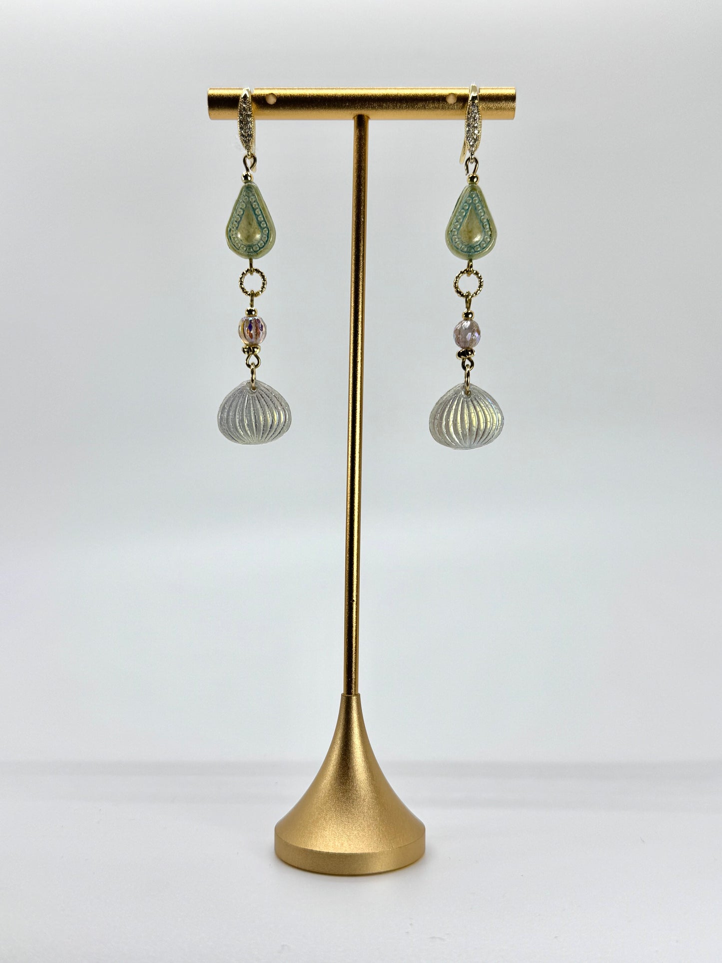 Pair of earrings on a gold stand against a white background