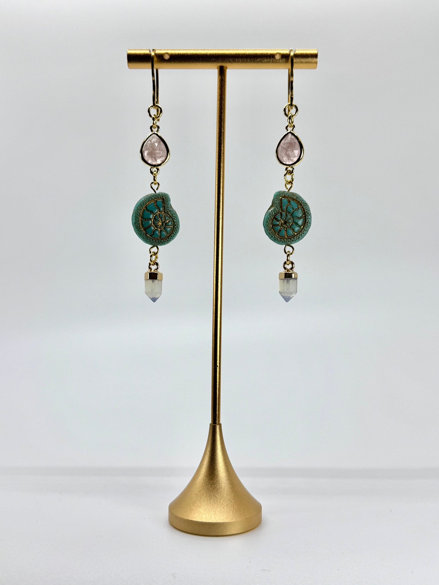 Pair of earrings with turquoise stones on a gold stand against a white background
