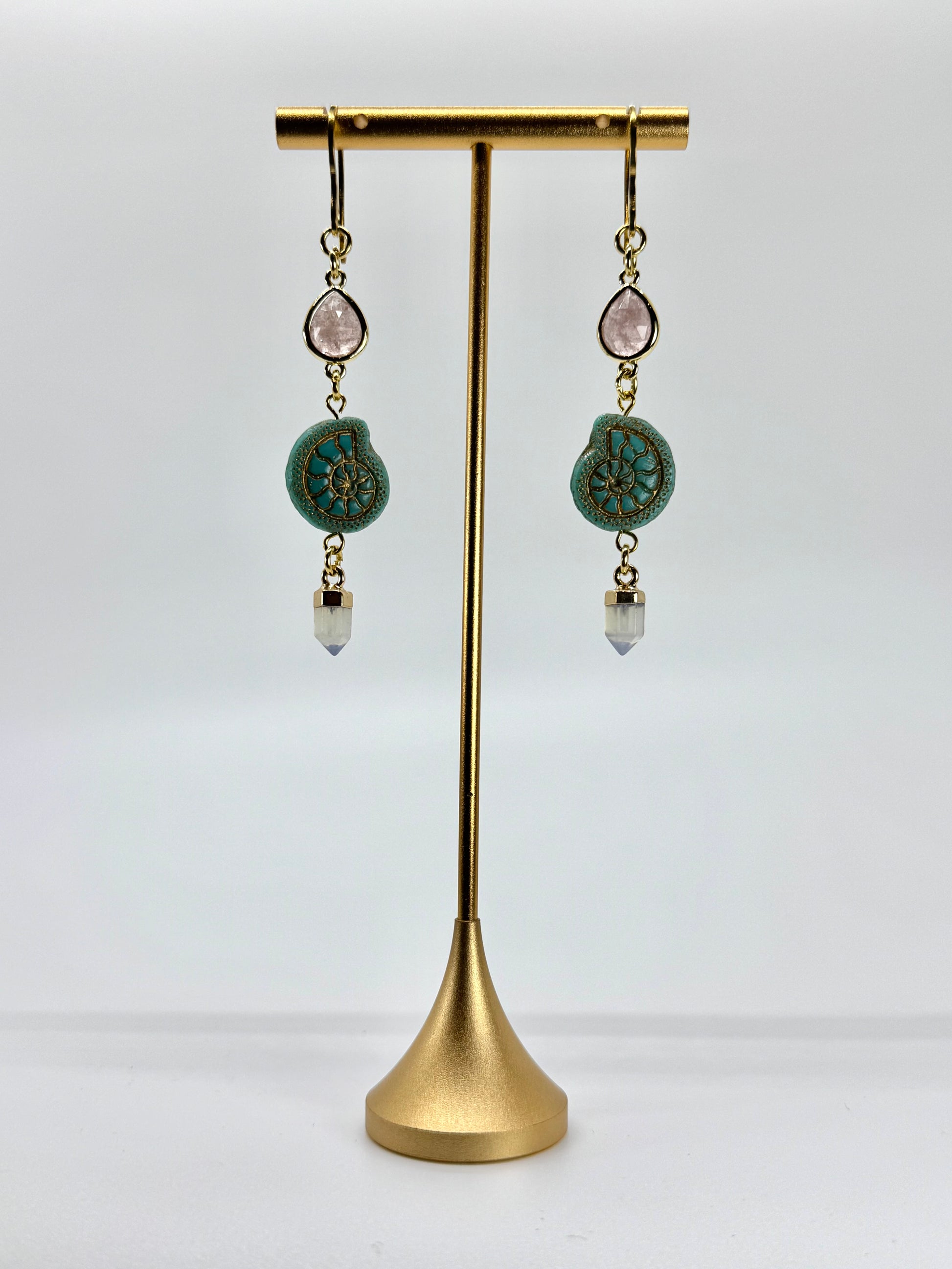 Pair of earrings with turquoise stones on a gold stand against a white background