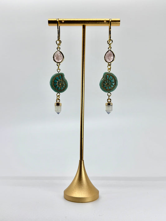 Pair of earrings with turquoise stones on a gold stand against a white background
