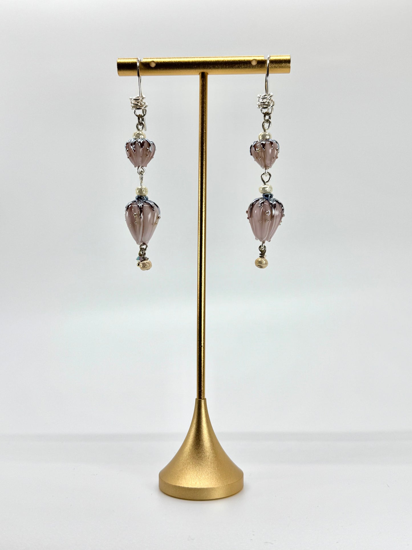 Pair of earrings on a gold stand against a white background