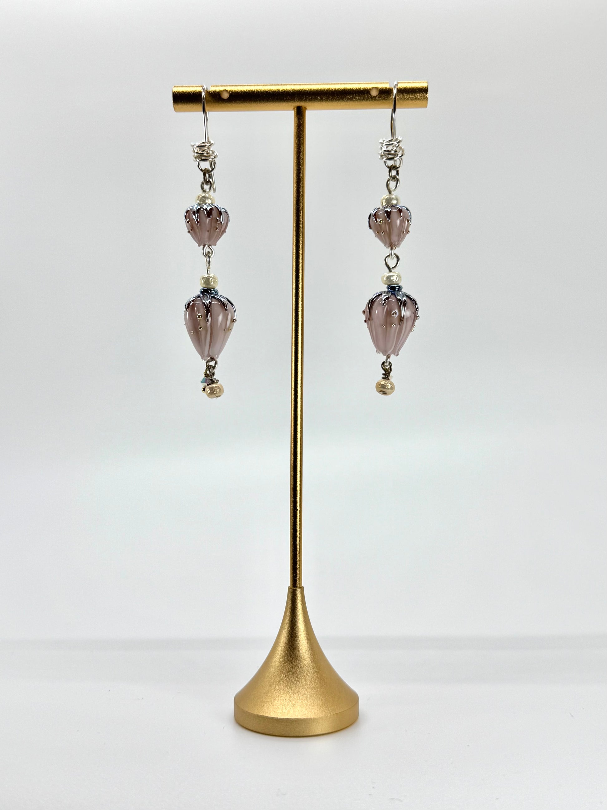 Pair of earrings on a gold stand against a white background