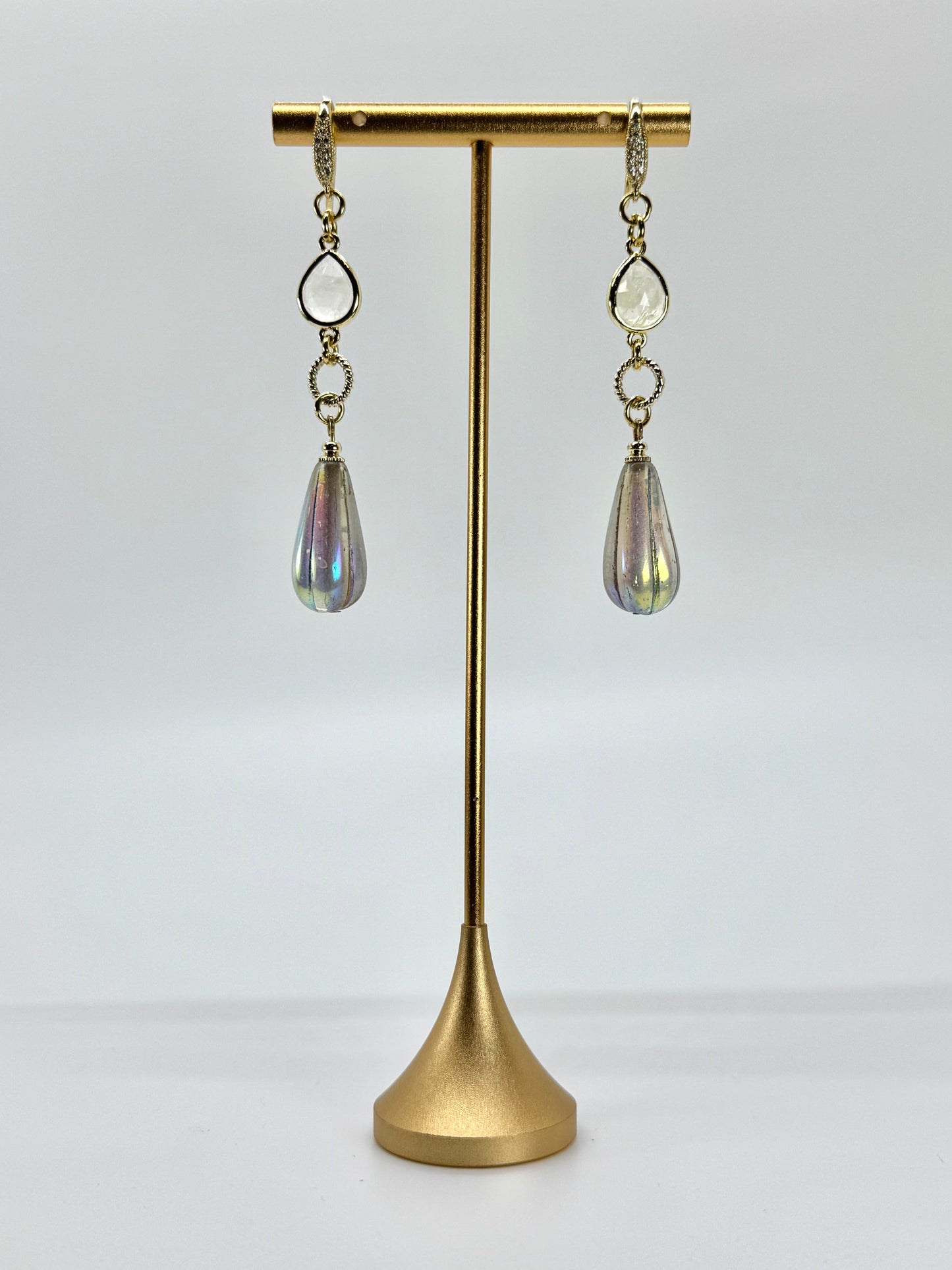 Pair of earrings on a gold stand against a white background