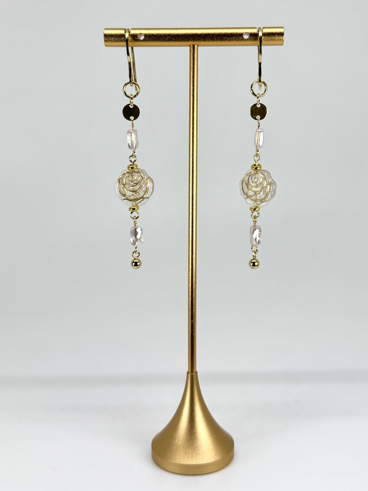 Pair of earrings on a gold stand against a white background