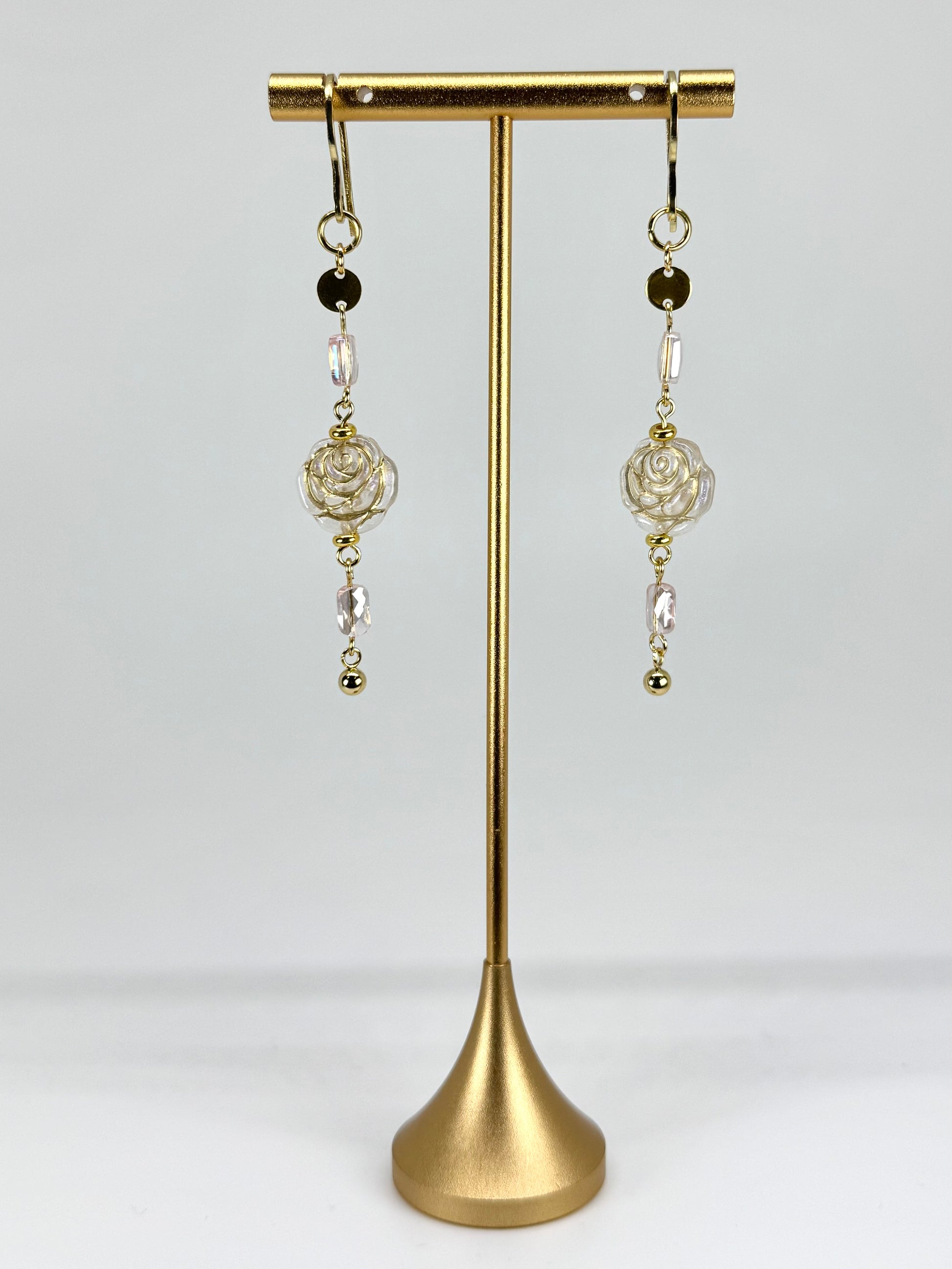 Pair of earrings on a gold stand against a white background