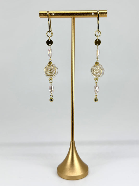 Pair of earrings on a gold stand against a white background