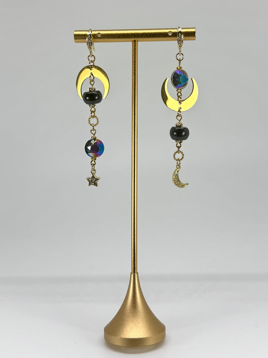 Pair of earrings on a gold stand against a gray background