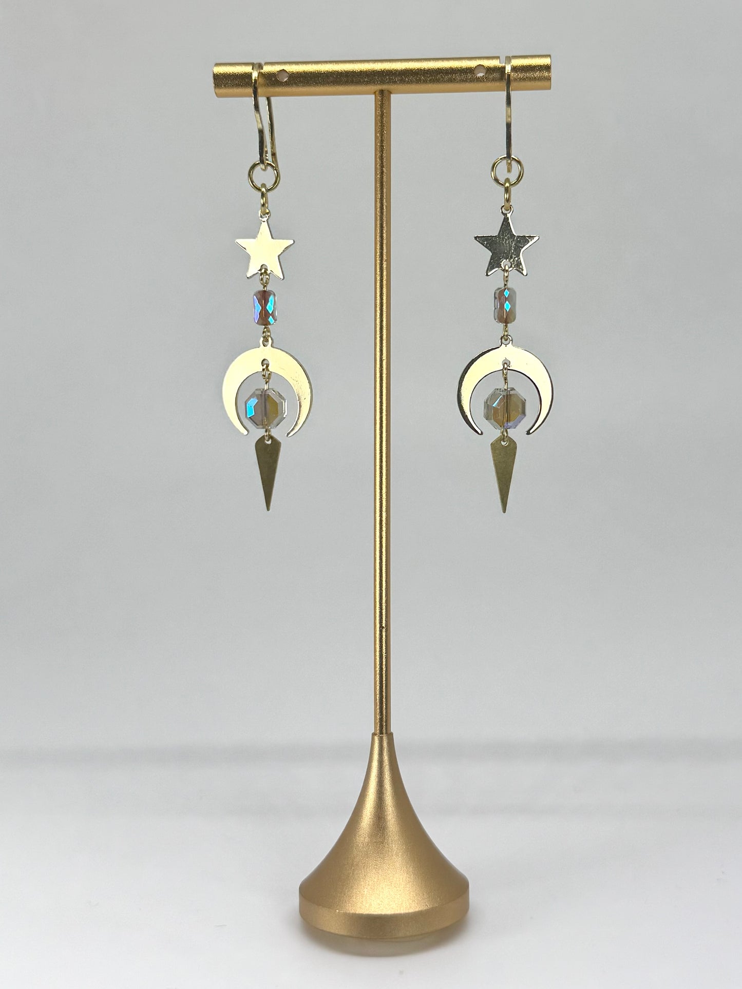 Pair of earrings on a gold stand against a white background
