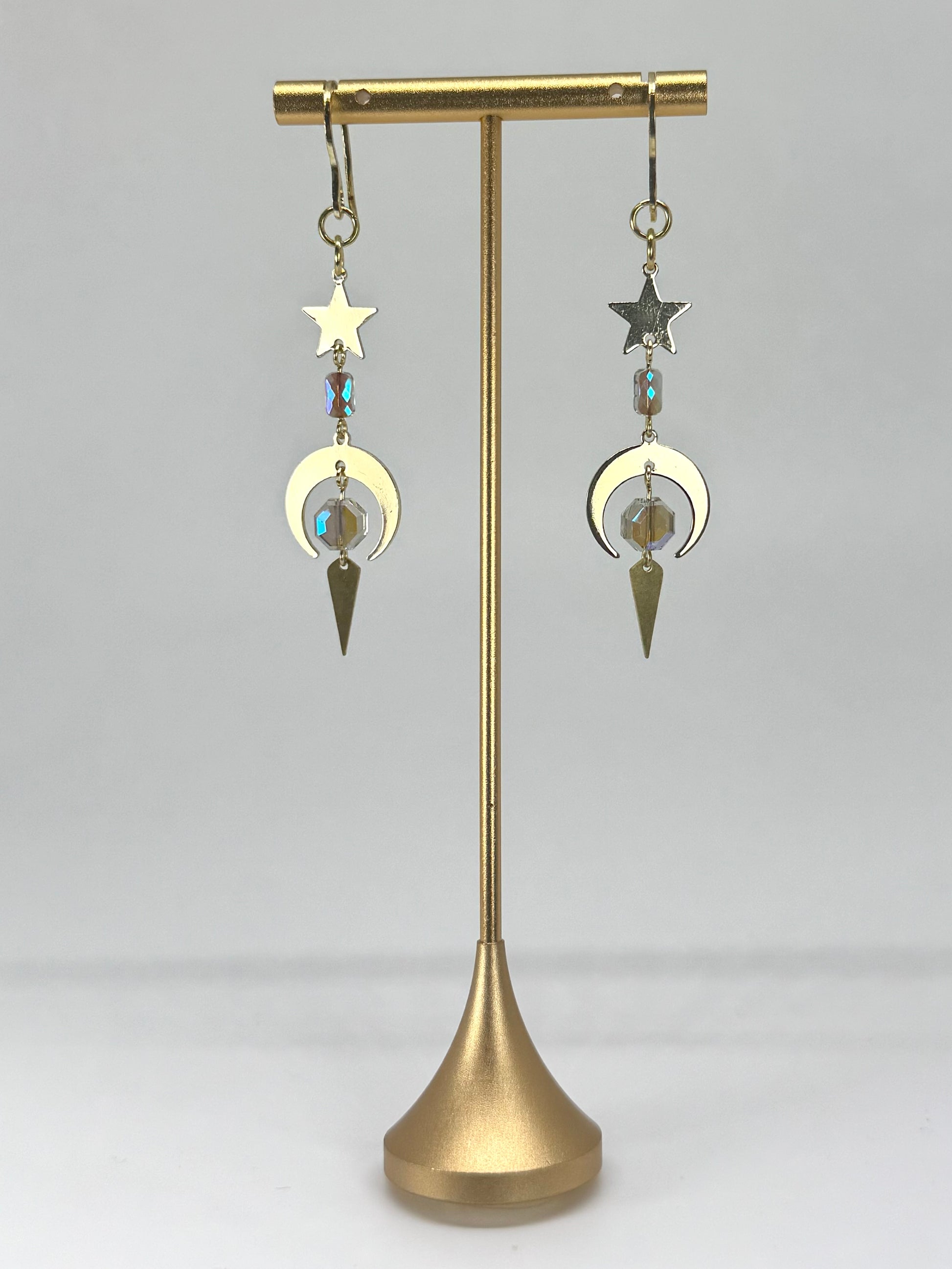 Pair of earrings on a gold stand against a white background