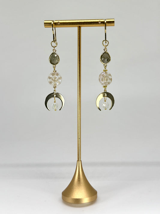 Pair of earrings with crystal and moon phase design on a gold stand against a white background