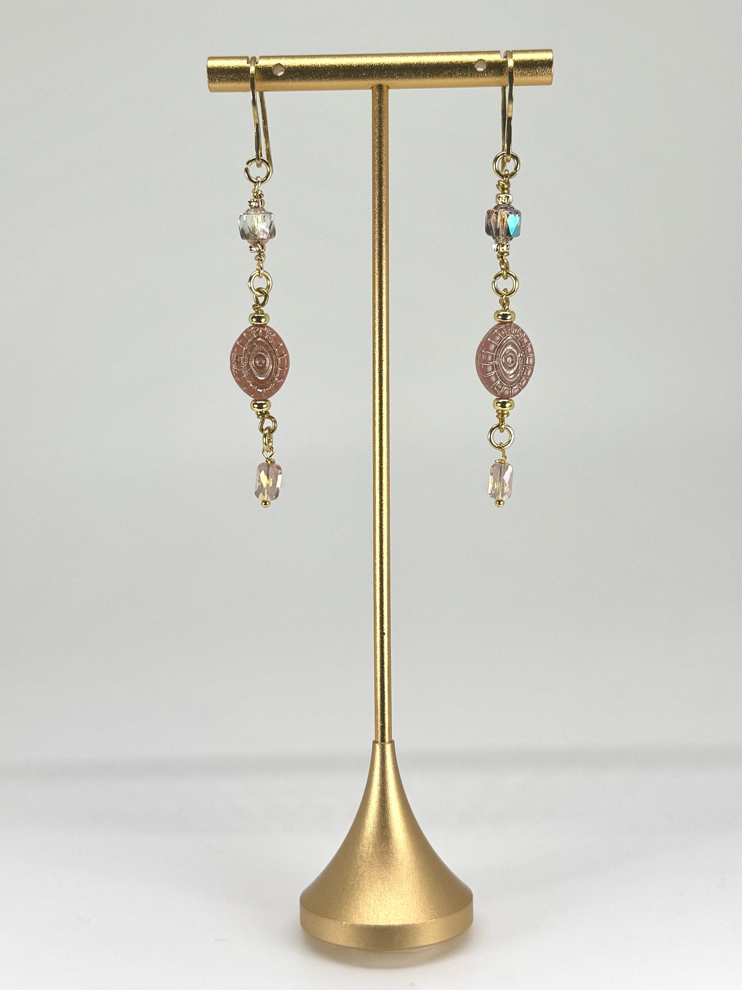 Pair of earrings on a gold stand against a white background