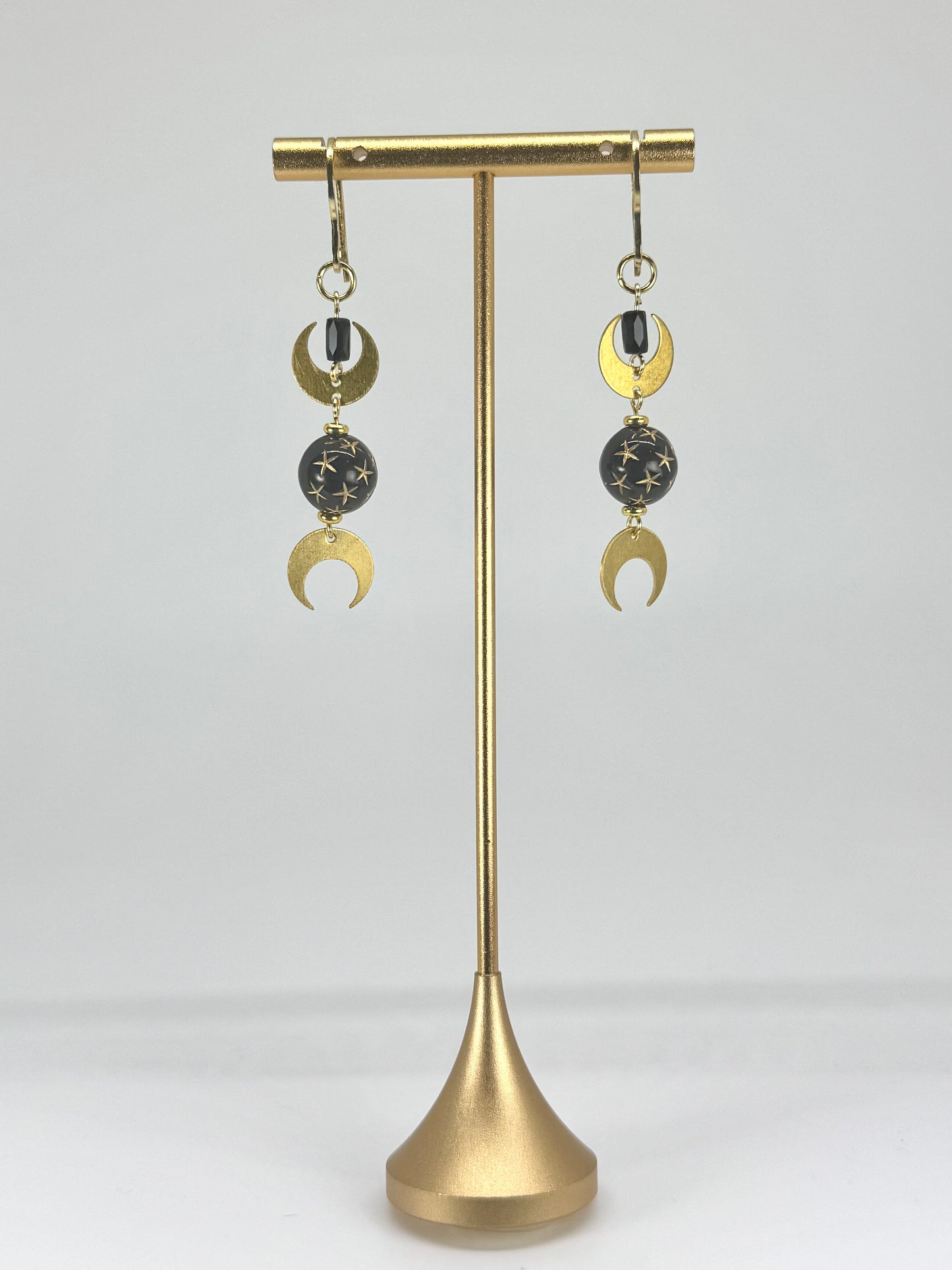 Pair of earrings on a gold stand against a white background