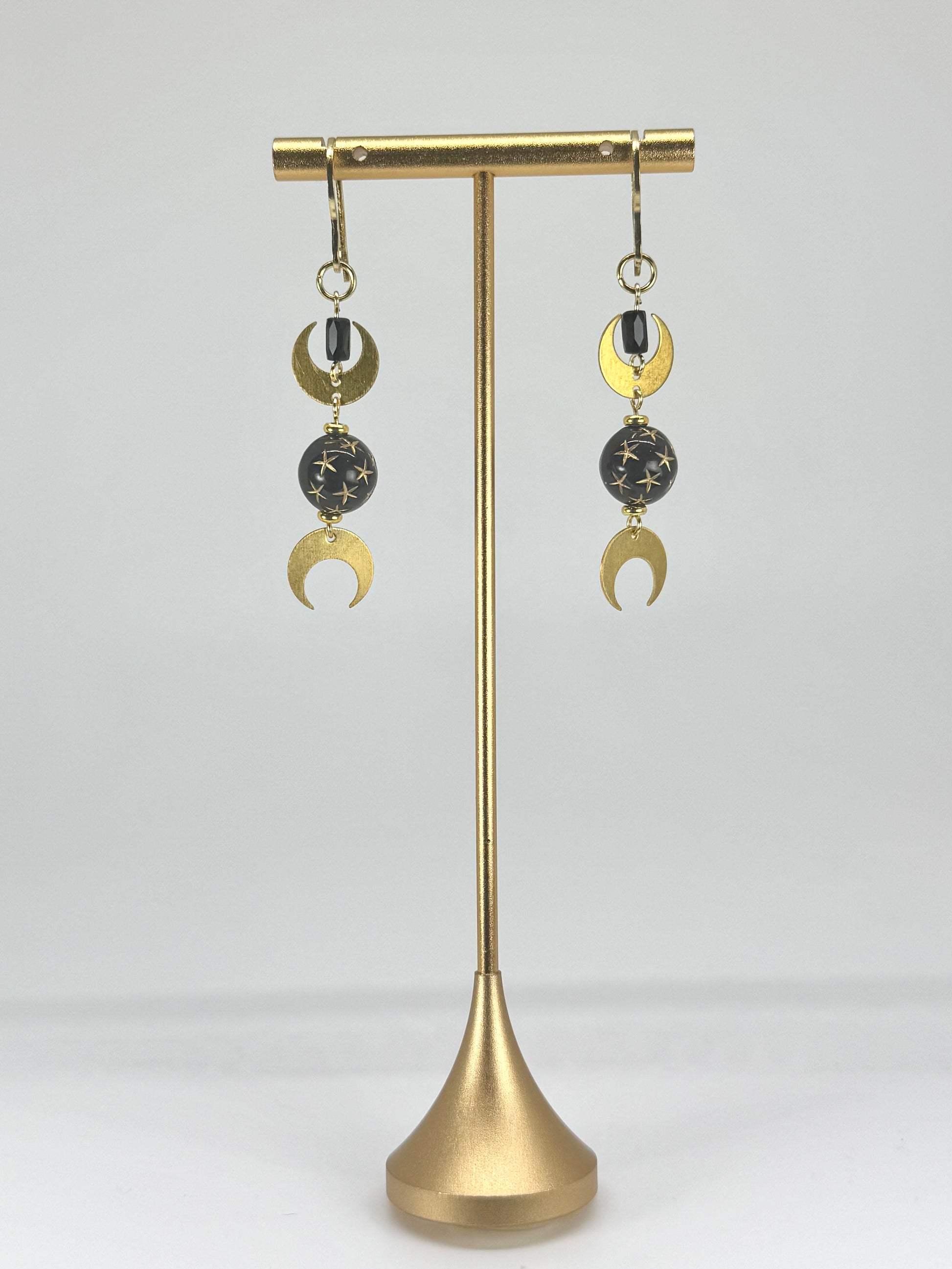 Pair of earrings on a gold stand against a white background