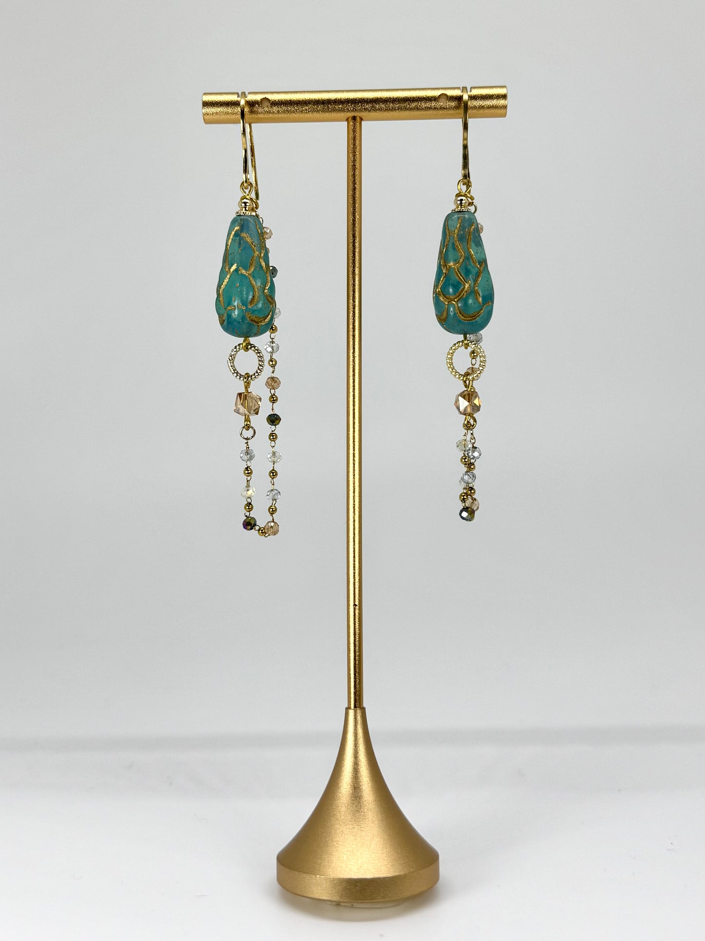 Pair of earrings on a gold stand against a white background