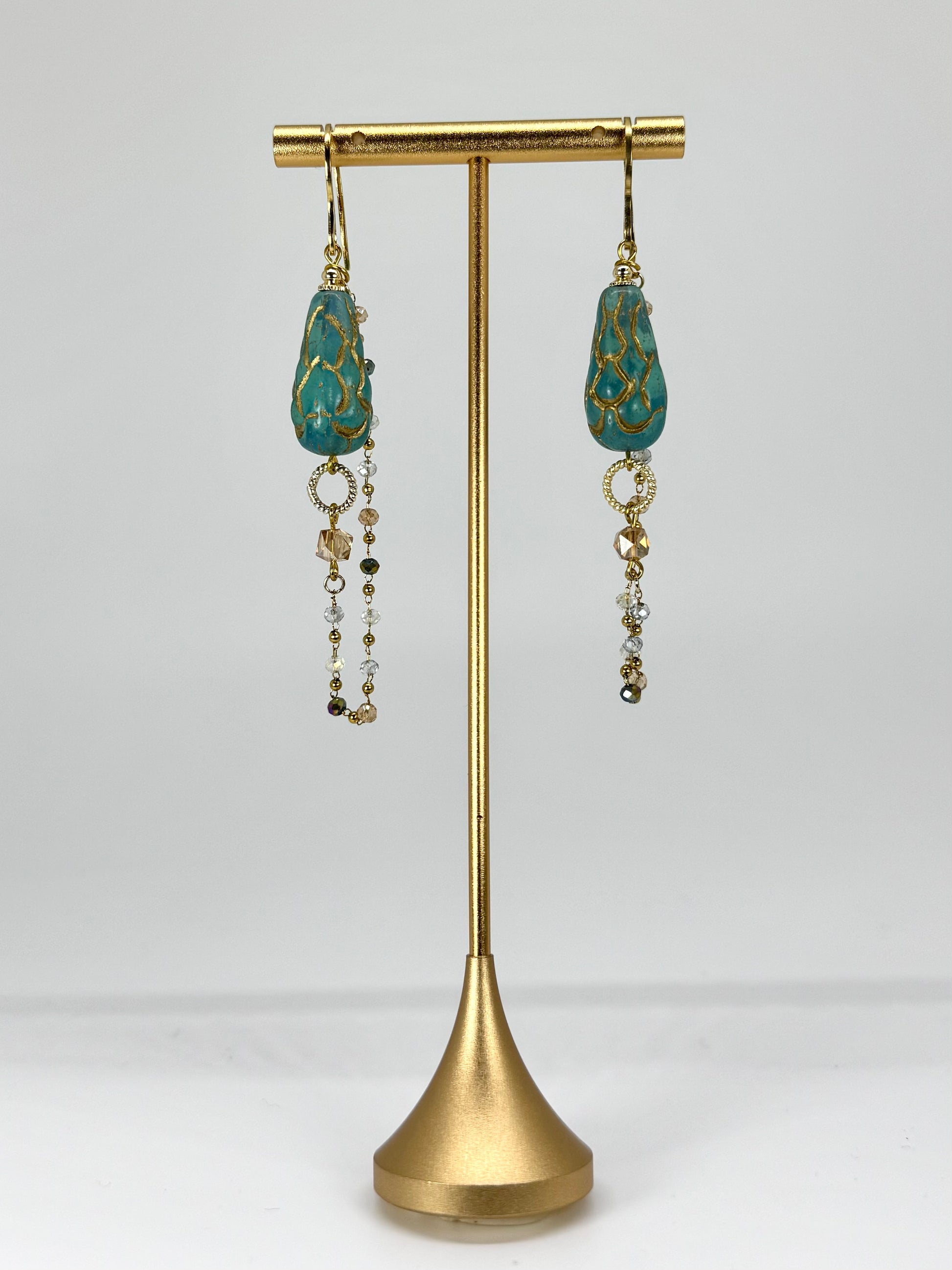 Pair of earrings on a gold stand against a white background