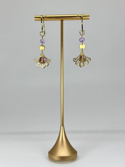 Pair of gold earrings with purple and yellow beads on a gold stand against a gray background