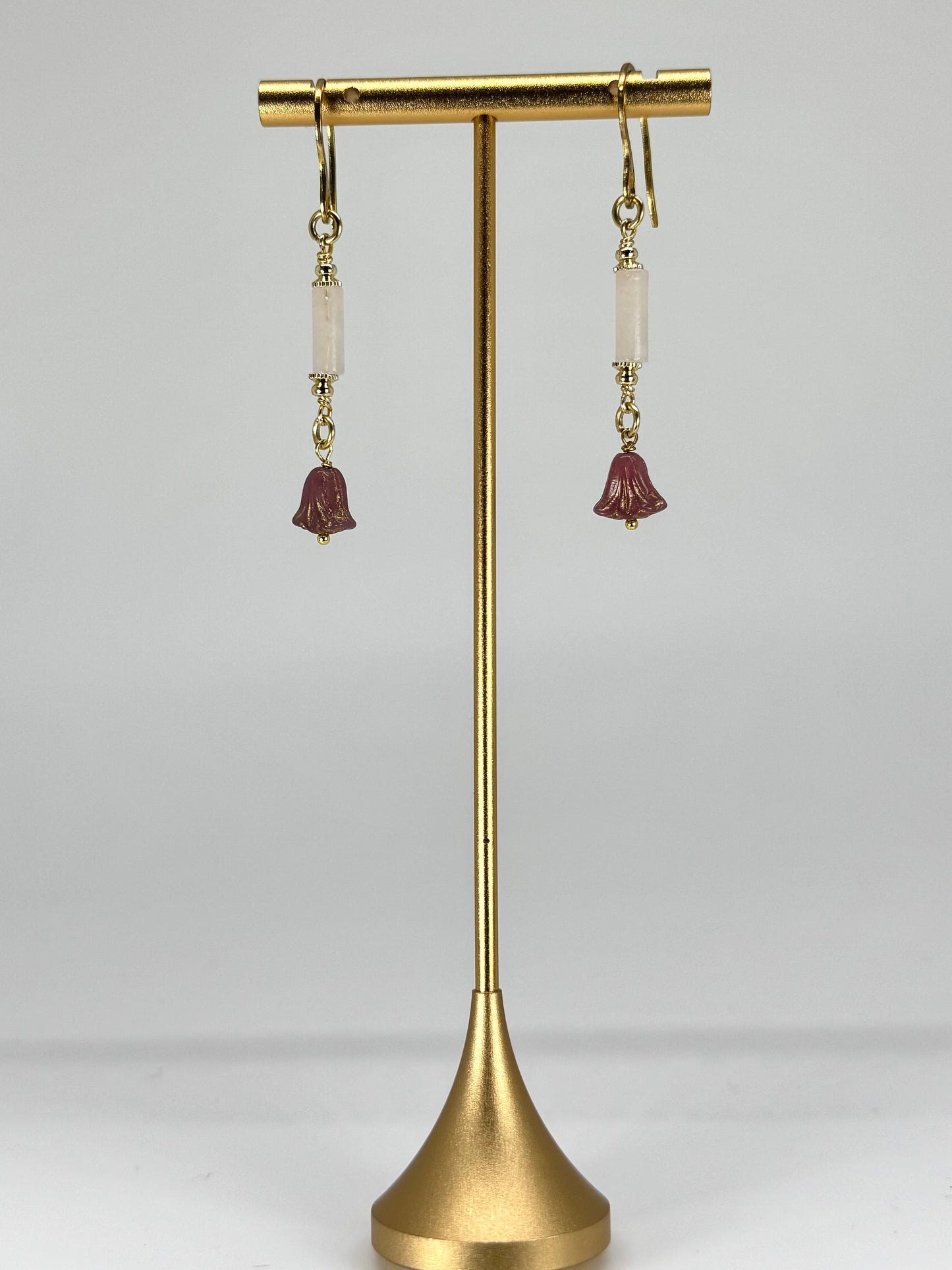Pair of earrings on a gold stand against a white background