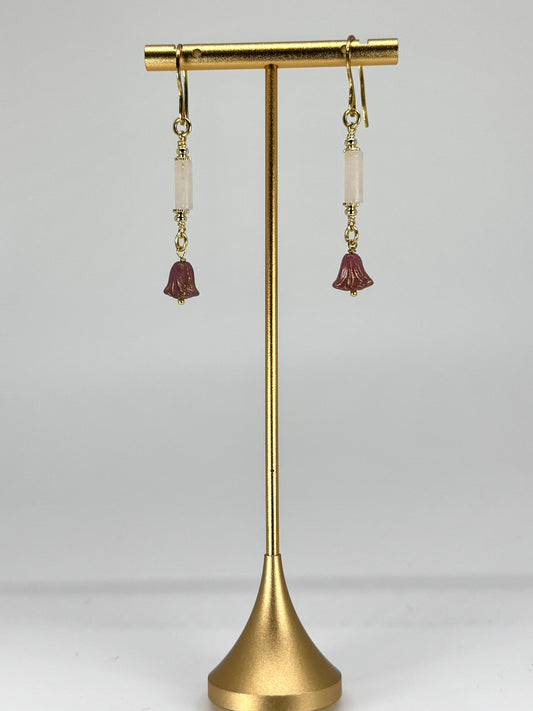 Pair of earrings on a gold stand against a white background